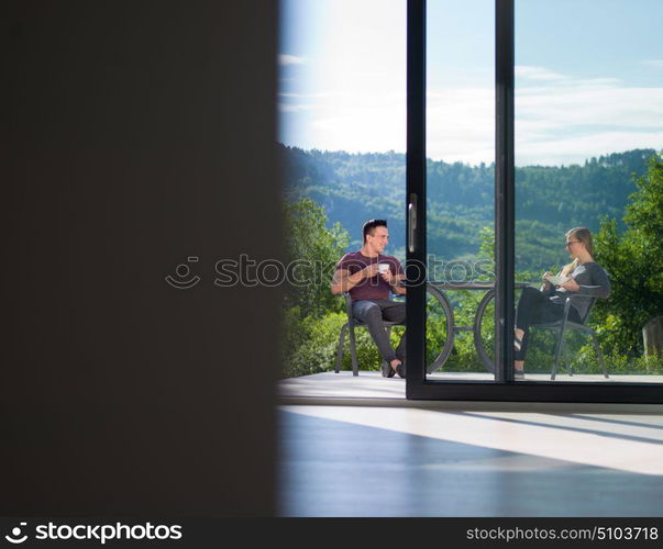 young beautiful handsome couple enjoying morning coffee and breakfast in front of their luxury home villa