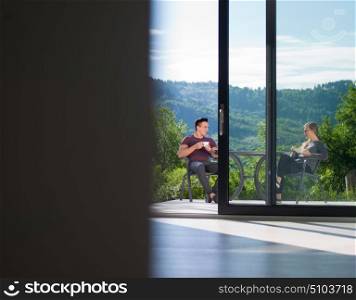 young beautiful handsome couple enjoying morning coffee and breakfast in front of their luxury home villa