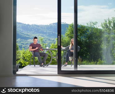 young beautiful handsome couple enjoying morning coffee and breakfast in front of their luxury home villa