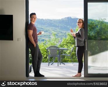 young beautiful handsome couple enjoying morning coffee and breakfast on the door of their luxury home villa