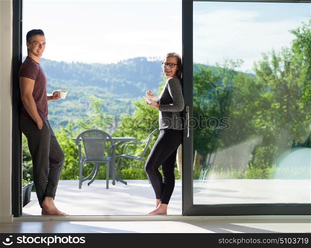 young beautiful handsome couple enjoying morning coffee and breakfast on the door of their luxury home villa
