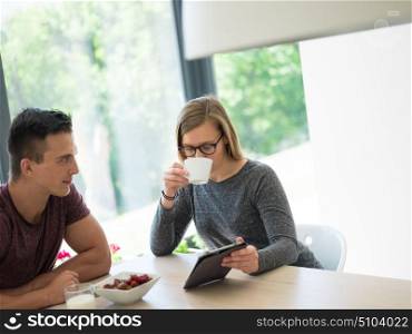 young beautiful handsome couple enjoying morning coffee and strawberries in their luxurious home villa
