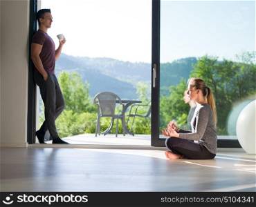 young beautiful handsome couple enjoying morning coffee and Yoga exercises on the door of their luxury home villa