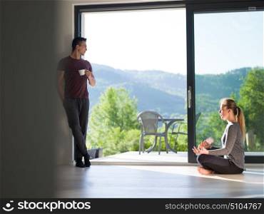 young beautiful handsome couple enjoying morning coffee and Yoga exercises on the door of their luxury home villa