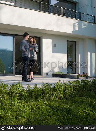 young beautiful handsome couple enjoying morning coffee in front of their luxury home villa