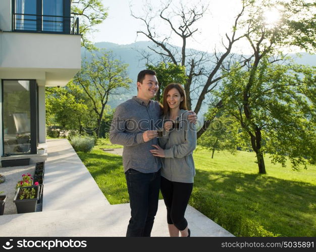 young beautiful handsome couple enjoying morning coffee in front of their luxury home villa