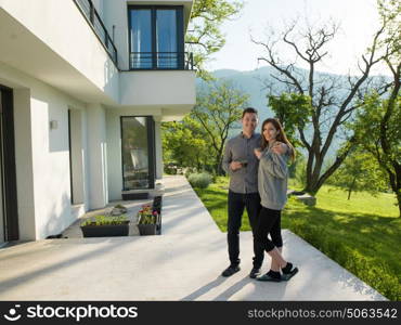 young beautiful handsome couple enjoying morning coffee in front of their luxury home villa