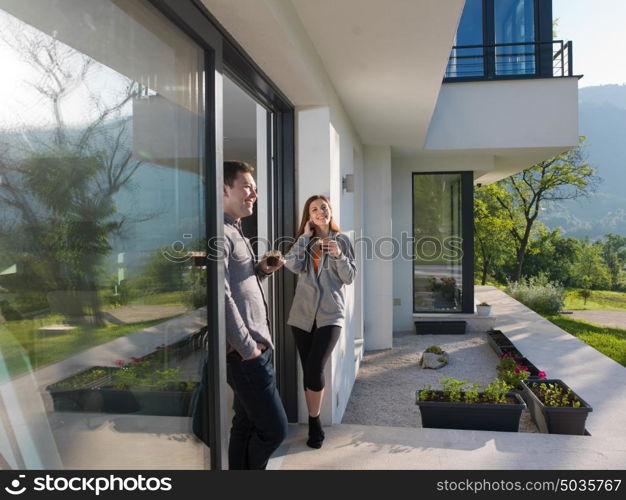 young beautiful handsome couple enjoying morning coffee on the door of their luxury home villa