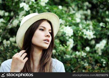 young beautiful hipster girl with long brunette hair in the Park near the tree Jasmine