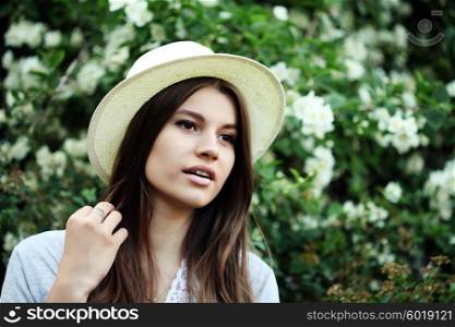 young beautiful hipster girl with long brunette hair in the Park near the tree Jasmine