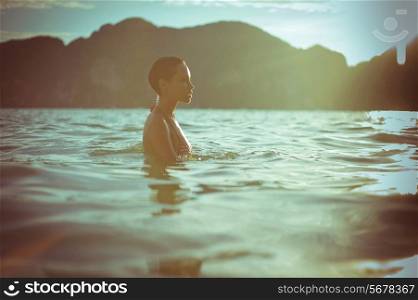 Young beautiful lady in the sea at sunset