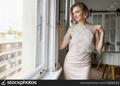 young beautiful lady posing in the living room next to a window
