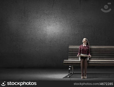 Young beautiful lady sitting on bench and reading book