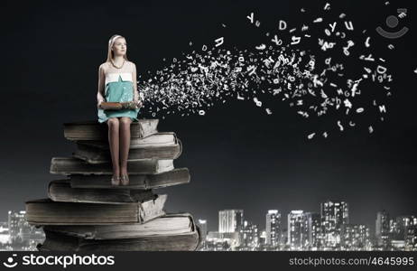 Young beautiful lady sitting on pile of old books. I like reading