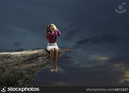 Young beautiful lady sitting on rock edge and reading book