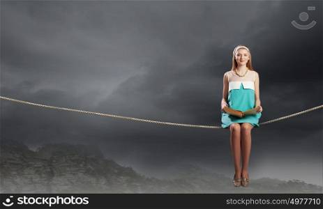 Young beautiful lady sitting on rope with book in hands. Girl with book
