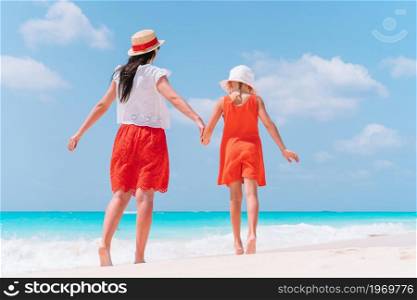 Young beautiful mother and her adorable little daughter have fun at tropical beach. Beautiful mother and daughter at Caribbean beach enjoying summer vacation.