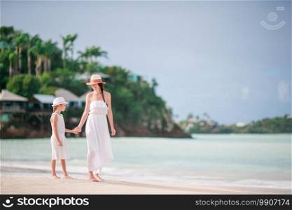 Young beautiful mother and her adorable little daughter have fun at tropical beach. Beautiful mother and daughter on Caribbean beach