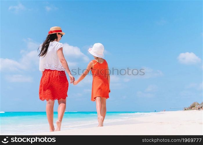 Young beautiful mother and her little daughter on the beach. Beautiful mother and daughter at the beach enjoying summer vacation.