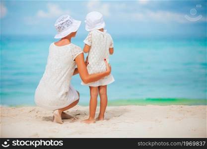 Young beautiful mother and her little daughter on the beach. Beautiful mother and daughter at the beach enjoying summer vacation