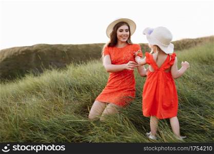 young beautiful mother and little daughter walking on nature on summer day vacation. Mom and girl playing in the field at the sunset time. mothers day. Concept of friendly family.. young beautiful mother and little daughter walking on nature on summer day vacation. Mom and girl playing in the field at the sunset time. mothers day. Concept of friendly family