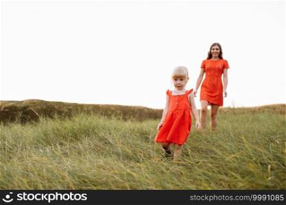 young beautiful mother and little daughter walking on nature on summer day vacation. Mom and girl playing in the field at the sunset time. mothers day. Concept of friendly family.. young beautiful mother and little daughter walking on nature on summer day vacation. Mom and girl playing in the field at the sunset time. mothers day. Concept of friendly family