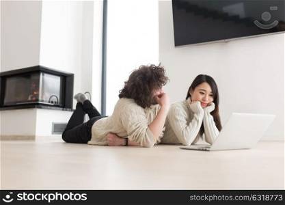 Young beautiful multiethnic couple using a laptop and doing shopping online at home on the floor
