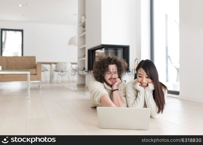 Young beautiful multiethnic couple using a laptop and doing shopping online at home on the floor