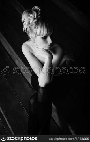 Young beautiful naked woman sitting on wooden stairs