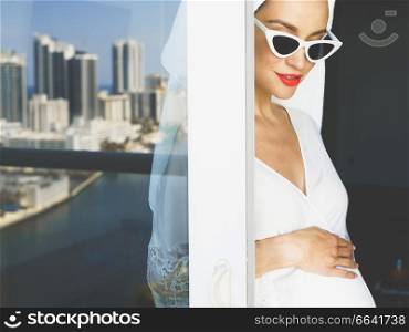 Young beautiful pregnant woman on balcony . Beautiful morning. Fashion and beauty