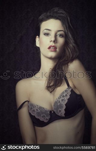 young beautiful sexy girl wearing a fashion bra , and posing on dark background. she has hairstyle