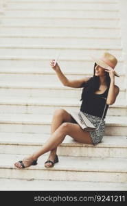 Young beautiful smiling woman in hat making selfie with smartphone outdoors