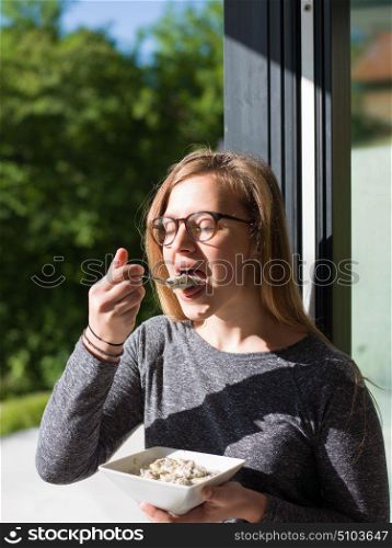 young beautiful successful woman eating breakfast in the doorway of her luxury home villa