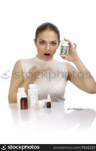 Young beautiful woman amazed by expensive pills - she showing a pill bottle wrapped up with a hundred dollars