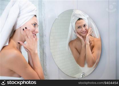Young beautiful woman applying cream on her face in front of the mirror
