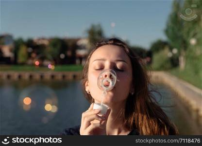 Young beautiful woman blow bubbles in the park