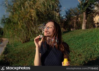 Young beautiful woman blow bubbles in the park