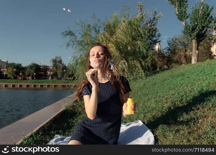 Young beautiful woman blow bubbles in the park