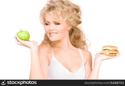 young beautiful woman choosing between burger and apple