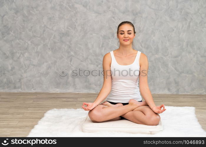 Young beautiful woman do yoga exercise on carpet at home living room. Healthy lifestyle and relaxation.