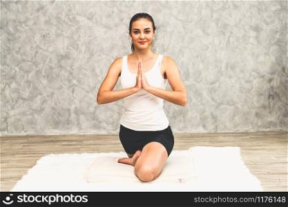 Young beautiful woman do yoga exercise on carpet at home living room. Healthy lifestyle and relaxation.