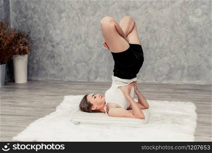 Young beautiful woman do yoga exercise on carpet at home living room. Healthy lifestyle and relaxation.