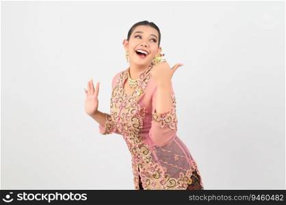 Young beautiful woman dress up in local culture in southern region standing and thumb up with cheerful and playful poseture on white background, copy space
