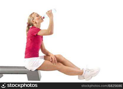 Young beautiful woman drinks water after playing sports