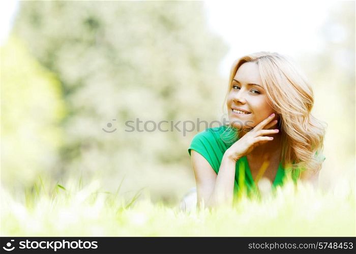 Young beautiful woman enjoying laying on fresh green grass