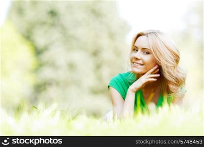 Young beautiful woman enjoying laying on fresh green grass