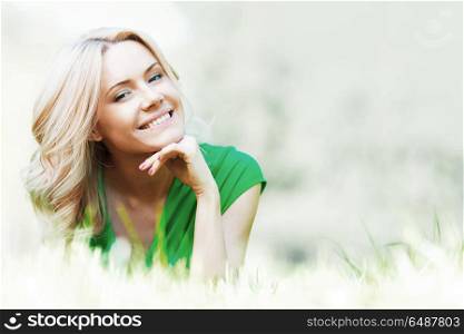 Young beautiful woman enjoying laying on fresh green grass. Woman on grass