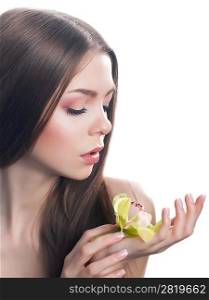 Young beautiful woman face with fresh orchid flower close-up portrait. Clean healthy skin