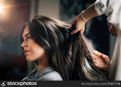 Young beautiful woman getting new hair style in beauty salon.. Hairstylist Fixing Woman’s Hair 