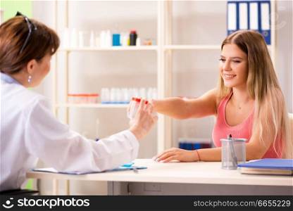 Young beautiful woman giving urine test to doctor 